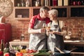 Cheerful senior couple clinking with wine glasses in kitchen Royalty Free Stock Photo