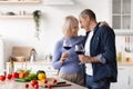 Cheerful senior couple clinking with wine glasses in kitchen Royalty Free Stock Photo