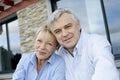 Cheerful senior couple in front of house