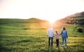 Senior couple with granddaughter outside in spring nature, walking at sunset. Royalty Free Stock Photo