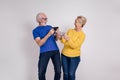 Cheerful senior couple looking at each other and playing video game over phones on white background Royalty Free Stock Photo