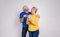 Cheerful senior couple looking at each other and reading good news over phone on white background Royalty Free Stock Photo