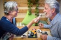 Cheerful senior couple, a man and a woman with gray hair, enjoying Japanese sushi. Outdoors on a wooden table Royalty Free Stock Photo