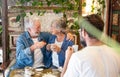 Cheerful senior couple and mature son inside a coffee shop having break with coffee, cappuccino and fruit cake. Three people Royalty Free Stock Photo