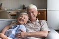 Cheerful senior couple relaxing on home couch, hugging with love