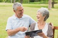 Cheerful senior couple using digital tablet on bench at park Royalty Free Stock Photo