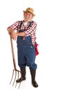 Cheerful senior farmer leaning on hay fork