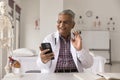 Cheerful senior Indian doctor man giving online consultation on smartphone Royalty Free Stock Photo