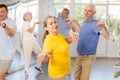 Cheerful senior lady practicing twist with male partner in dance studio