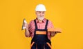 cheerful senior man bricklayer in helmet on yellow background