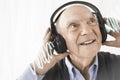 Cheerful senior man listening music through headphones against white background Royalty Free Stock Photo