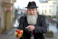 Cheerful senior man showing gift box in his hand and looking at camera standing outdoors. Royalty Free Stock Photo