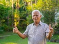 Cheerful senior man showing thumb up gesture by two hands over in his garden Royalty Free Stock Photo