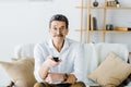 Cheerful senior man sitting on sofa and holding remote control Royalty Free Stock Photo