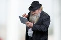 Cheerful senior man wearing classic black hat using digital tablet. Royalty Free Stock Photo