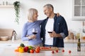Cheerful senior man and woman cooking together, drinking wine Royalty Free Stock Photo