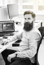 Cheerful senior programmer developer working in IT office, sitting at desk and coding, working on a project in software