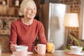 Cheerful senior woman eating breakfast and smiling