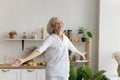 Cheerful senior woman enjoys carefree life dancing in the kitchen Royalty Free Stock Photo