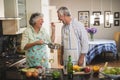 Cheerful senior woman feeding man in kitchen Royalty Free Stock Photo