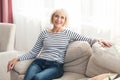 Cheerful senior woman feeling happy and relaxed, sitting on couch