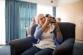 Cheerful senior woman holding kitten while sitting on armchair Royalty Free Stock Photo