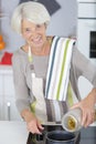 cheerful senior woman standing by stove in kitchen Royalty Free Stock Photo