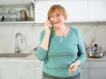 Cheerful senior woman talking on phone in her kitchen Royalty Free Stock Photo
