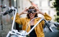 Cheerful senior woman traveller with motorbike in town. Royalty Free Stock Photo