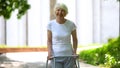 Cheerful senior woman with walking frame looking at camera outdoors, rehab Royalty Free Stock Photo