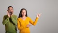 Cheerful shocked european old husband and wife with open mouth point finger at empty space