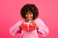 Cheerful shocked excited young black curly lady in casual with braces looks at box with gift
