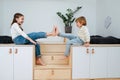 Cheerful siblings sitting on wooden elevation, presing bare feet