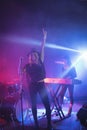 Cheerful singer singing while musician playing piano in illuminated nightclub Royalty Free Stock Photo