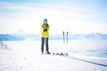 Cheerful skier girl in green jacket in front of snowy mountains
