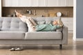 Cheerful sleepy blonde older lady lying on couch Royalty Free Stock Photo