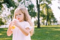 Cheerful small girl with curly hair drinking orange juice in the park Royalty Free Stock Photo