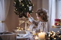 Cheerful small girl sitting indoors at Christmas, holding ornament. Royalty Free Stock Photo