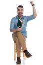 Cheerful smart casual man holding book and celebrating, laughing