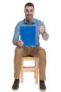 Cheerful smart casual man holding clipboard and giving thumbs up