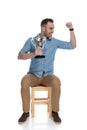 Cheerful smart casual man holding trophy and celebrating