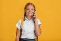 Cheerful smart european young girl student with pigtails and backpack talking on phone