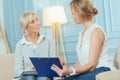 Cheerful smart financial advisor smiling while helping an aged woman