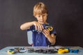 Cheerful smart schoolboy sitting at the table and constructing a robotic device at home