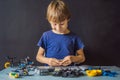 Cheerful smart schoolboy sitting at the table and constructing a robotic device at home