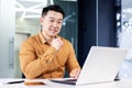 Cheerful and smiling Asian man working inside office, businessman in shirt using laptop, engineer developer programmer Royalty Free Stock Photo