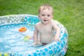 Portrait of cheerful smiling baby boy sitting in inflatable swimming pool at garden Royalty Free Stock Photo