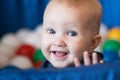 Cheerful smiling baby girl with blond hair and blue eyes sitting in the ball pit Royalty Free Stock Photo