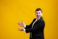 Cheerful smiling businessman wearing suit standing pointing hands aside on mock up copy space on yellow studio background Royalty Free Stock Photo