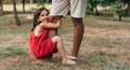 Cheerful smiling daughter spending time with his father swinging on daddy`s leg outdoors. Cute little girl playing with her dad i Royalty Free Stock Photo